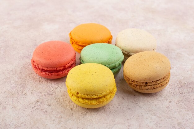 Uma vista frontal macarons franceses redondos e saborosos na mesa rosa bolo biscoito açúcar cor doce