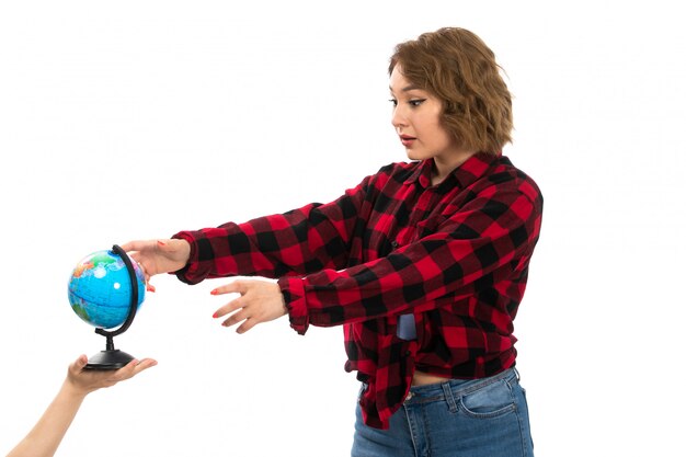 Uma vista frontal menina bonita camisa quadriculada vermelho-preta e calça jeans azul, tendo pouco globo no branco