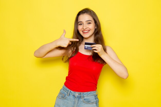 Uma vista frontal moça bonita camisa vermelha e calça jeans azul segurando o cartão com sorriso