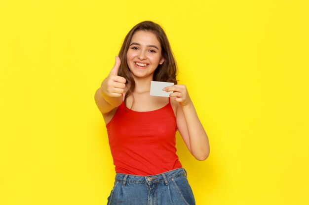 Uma vista frontal moça bonita camisa vermelha e calça jeans azul sorrindo e segurando o cartão