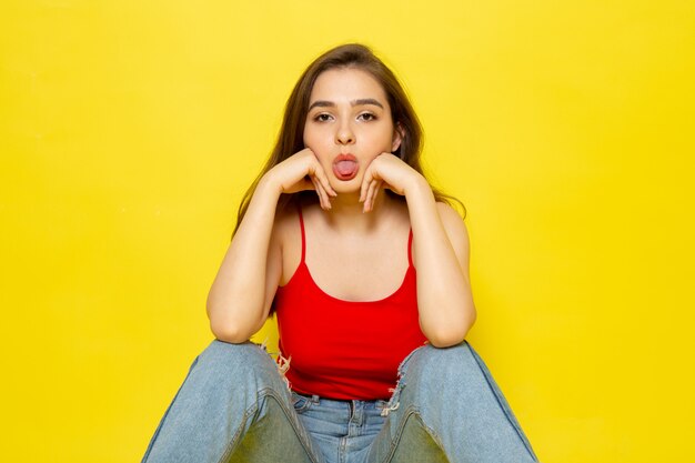 Uma vista frontal moça bonita camisa vermelha e calça jeans divertida posando