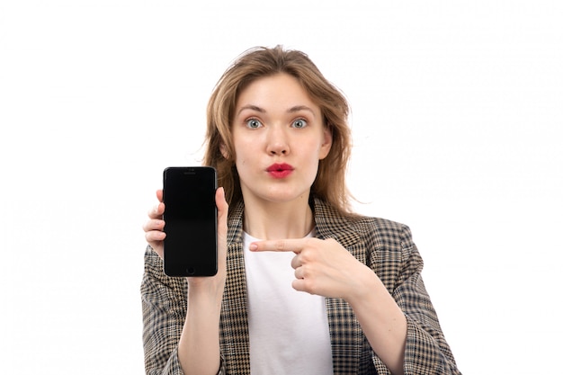 Foto grátis uma vista frontal moça bonita em jeans branco de camiseta preta e casaco segurando mostrando smartphone surpreendeu a expressão em branco