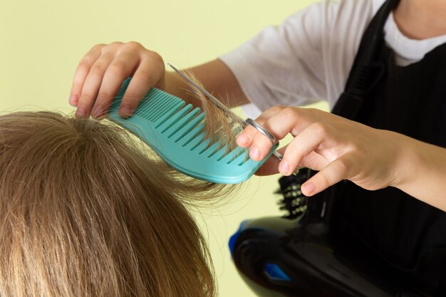 Uma vista frontal pouco cabeleireiro criança adorável trabalhando com penteado de meninos