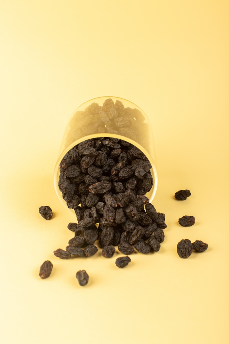 Foto grátis uma vista frontal preto frutas secas dentro de vidro plástico isolado sobre o fundo colorido creme frutas secas preto