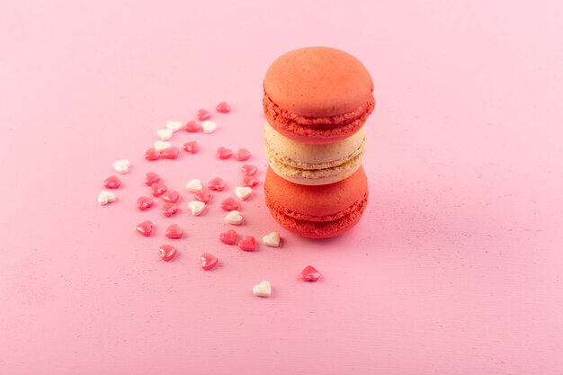 Uma vista frontal redonda de macarons franceses coloridos formados na mesa rosa