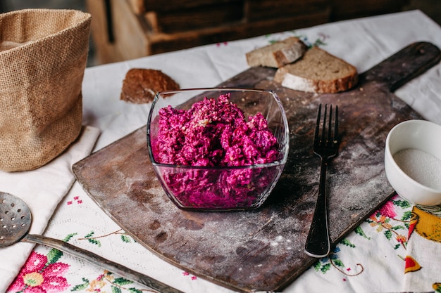 Uma vista frontal salada roxa de beterraba fatiada com nozes dentro de placa transparente salgada picante vitamina de legumes saborosos na mesa marrom