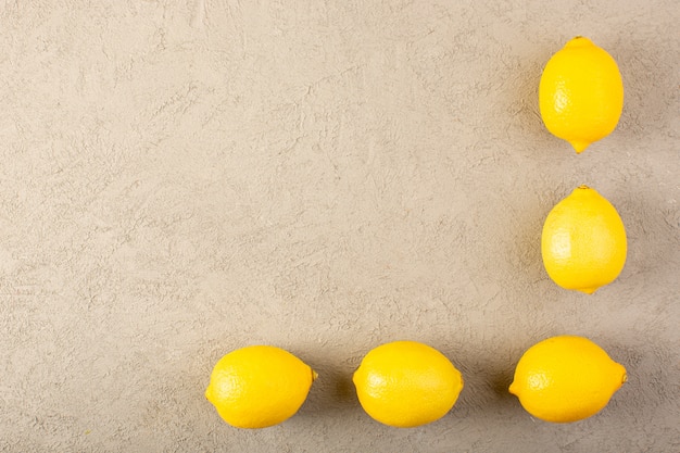 Foto grátis uma vista superior amarelo limões frescos maduros maduros e suculentos alinhado no fundo cinza frutas cítricas cor