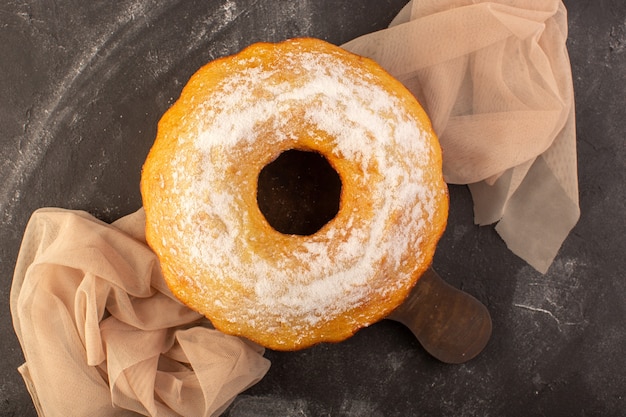 Uma vista superior assada em um bolo redondo com açúcar em pó na mesa de madeira