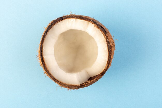 Uma vista superior coco nozes em fatias leitosas maduras frescas isoladas no azul gelado
