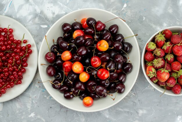 Uma vista superior de cerejas e morangos com cranberries dentro de um prato branco