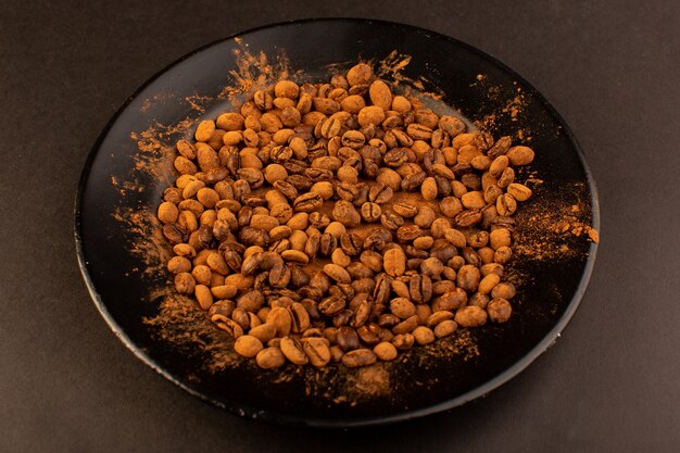 Uma vista superior de sementes de café marrom dentro da placa preta na mesa marrom