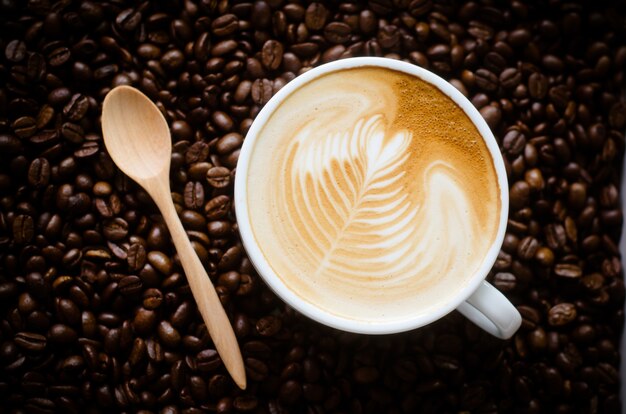 Uma xícara de arte latte em fundo de feijão de café