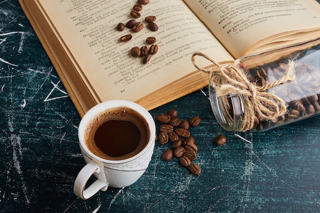 Foto grátis uma xícara de café com um livro à parte.