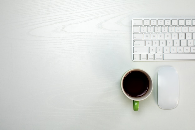 Uma xícara de café e teclado e mouse sem fio