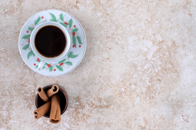 Foto grátis uma xícara de café e um pequeno pacote de paus de canela