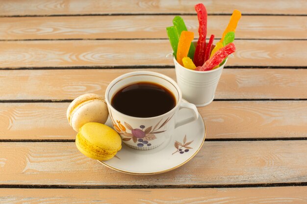 Uma xícara de café quente e forte com macarons franceses e geleia na mesa rústica de cor creme beber café foto forte