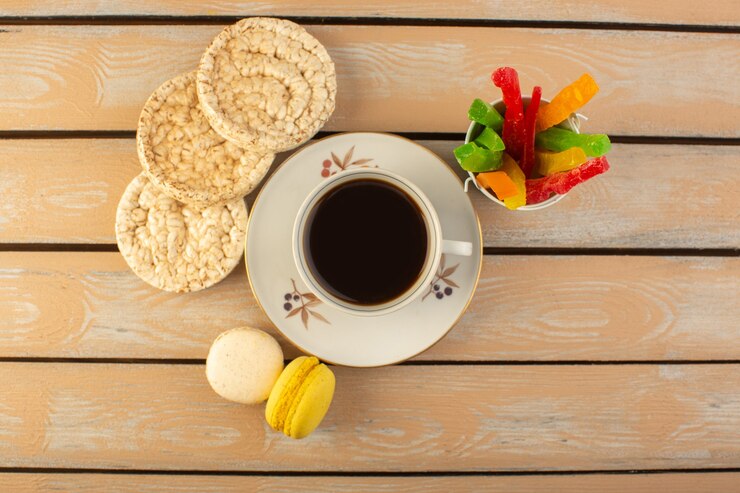 Foto grátis uma xícara de café quente e forte com macarons franceses e marmelada na mesa rústica de cor creme bebida café foto biscoito forte com vista de cima