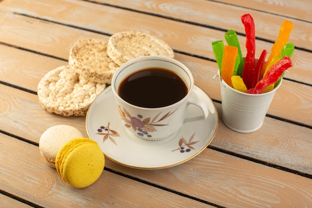 Uma xícara de café quente e forte com vista de cima com macarons franceses e geleia na mesa rústica de cor creme beber biscoito de foto de café