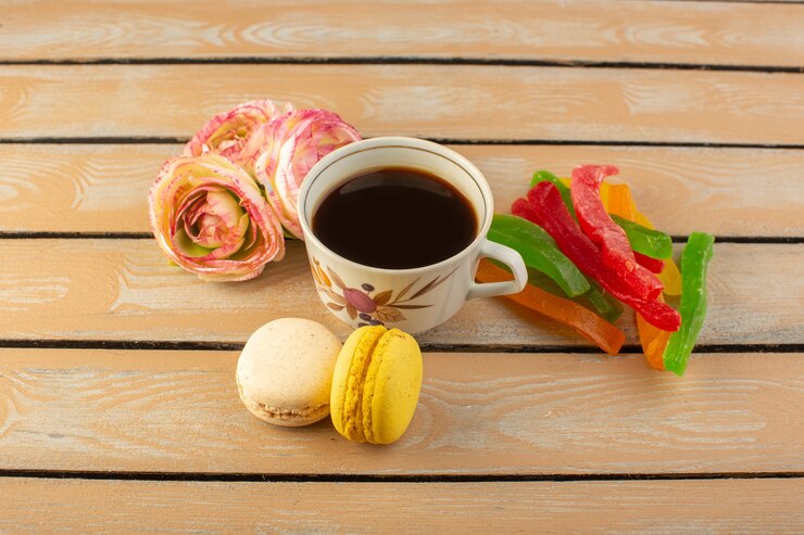 Foto grátis uma xícara de café quente e forte com vista de cima com macarons franceses e geleia na mesa rústica de cor creme bebida café foto doce biscoito