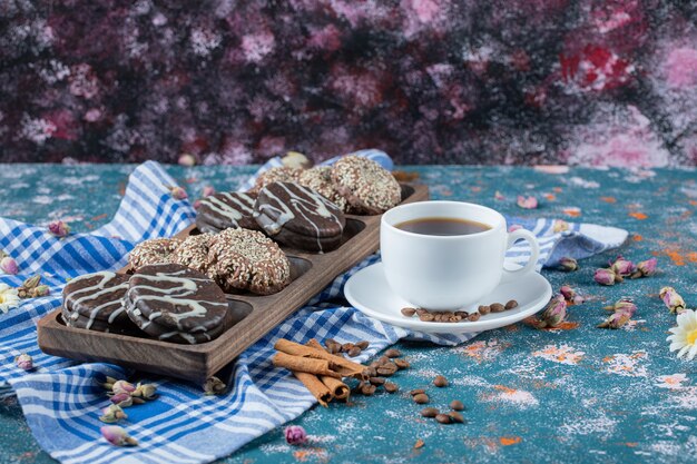 Uma xícara de café servida com biscoitos de chocolate.