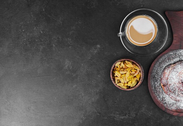 Uma xícara de cappuccino com frutas secas e pão doce.