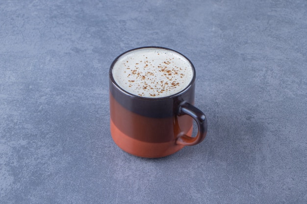 Foto grátis uma xícara de cappuccino com leite, sobre o fundo azul.