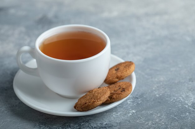 Uma xícara de chá aroma com biscoitos deliciosos.