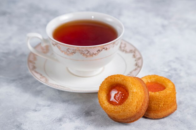 Uma xícara de chá com biscoitos caseiros de geléia de damasco.