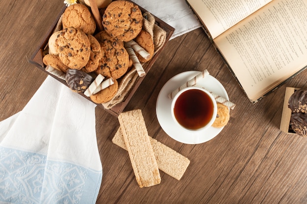 Uma xícara de chá com biscoitos de aveia e biscoitos em uma mesa de madeira