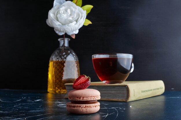 Uma xícara de chá com macaron rosa.