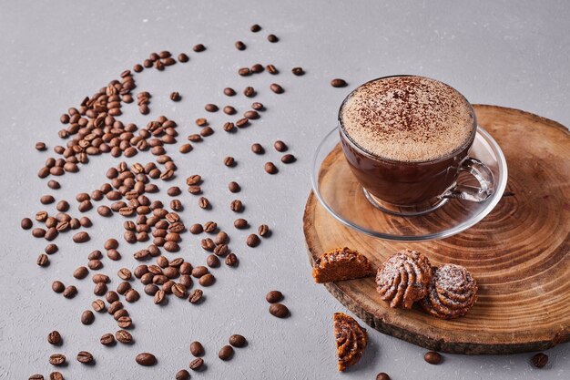 Uma xícara de chocolate quente com biscoitos ao redor.