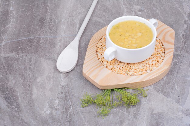 Uma xícara de sopa de feijão de ervilha em feijão cru em uma bandeja de madeira.