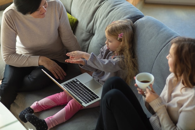 União. Família amorosa feliz. Avó, mãe e filha passando um tempo juntas. Assistindo cinema, usando laptop, rindo. Dia das mães, celebração, fim de semana, férias e conceito de infância.