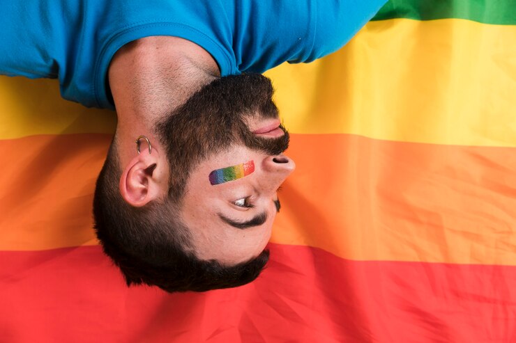 Foto grátis upside amanhecer jovem deitado no arco-íris bandeira lgbt