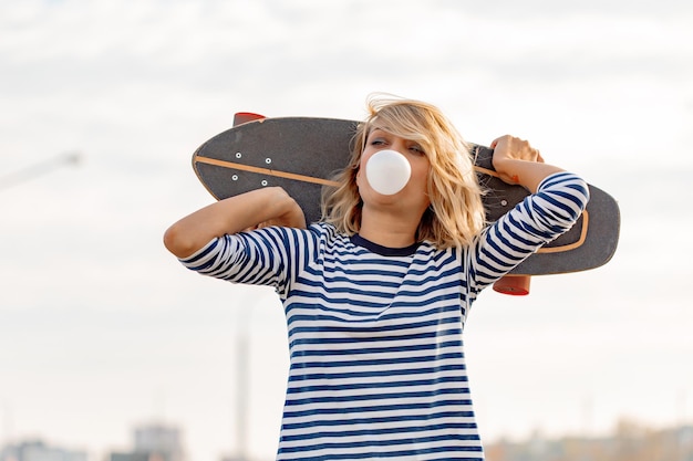 Urbana elegante jovem andando com skate. retrato ao ar livre do modelo de mulher esporte ativo. estilo de vida saudável. esportes extremos. olhar de moda, retrato de hipster ao ar livre. fechar o retrato de um prett