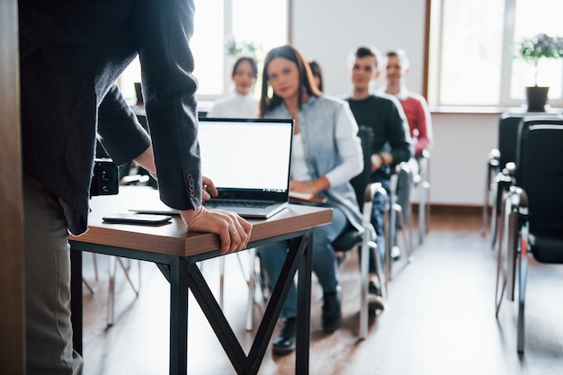 Usando laptop. Grupo de pessoas em conferência de negócios em sala de aula moderna durante o dia