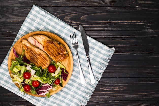 Utensílios perto de frango assado e salada