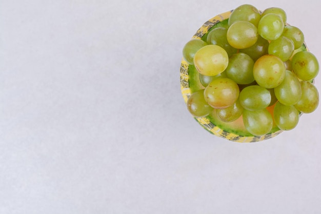 Foto grátis uvas ao meio cortadas melão verde na mesa branca.