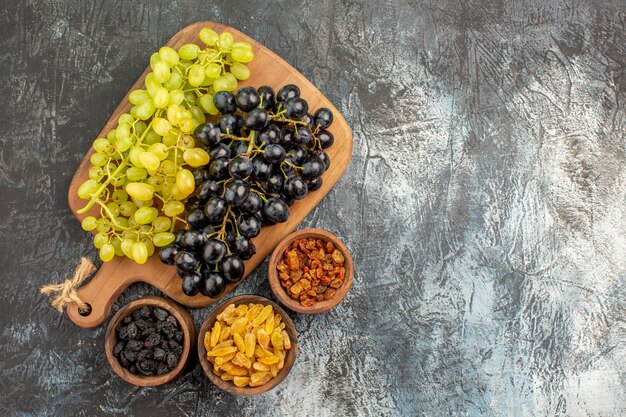 Foto grátis uvas apetitosas cachos de uvas na tábua de madeira taças de frutas secas