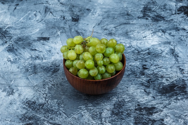 Foto grátis uvas brancas em uma tigela, close-up em um fundo de mármore azul escuro