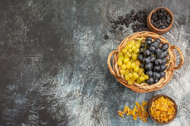 Uvas com vista de cima em close-up uma cesta de cachos de uvas entre duas tigelas de frutas secas