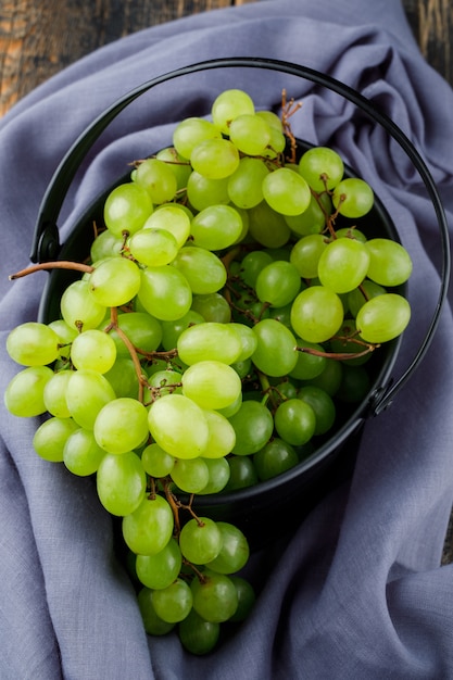 Uvas em um balde na superfície de madeira. configuração plana.