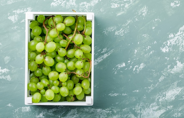 Foto grátis uvas em uma vista superior da caixa de madeira em um fundo de gesso sujo