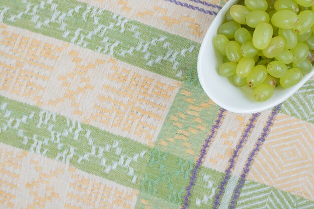 Uvas frescas em uma tigela branca na toalha de mesa.