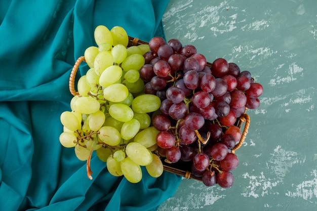 Foto grátis uvas maduras em uma cesta plana sobre gesso e tecido