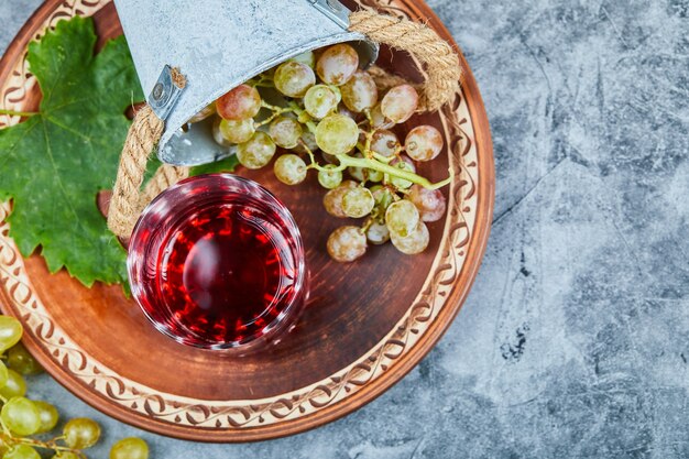 Uvas verdes e uma taça de vinho tinto na mesa.