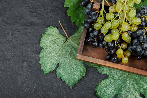 Uvas verdes e vermelhas em uma bandeja de madeira.