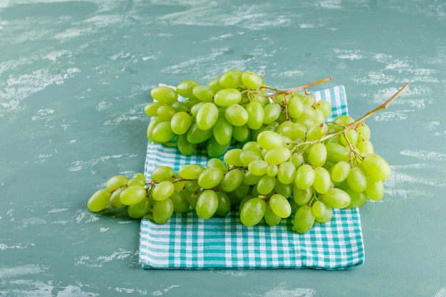 Foto grátis uvas verdes em gesso e fundo de pano de piquenique, vista de alto ângulo.