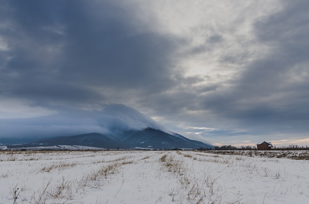 vale coberto de neve sob o céu escuro e nublado