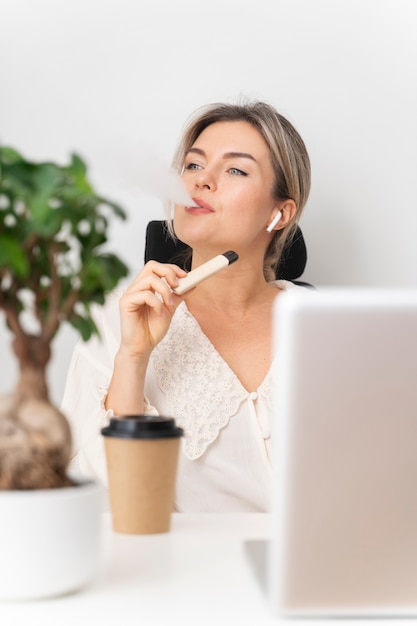 Foto grátis vaping de mulher de negócios de tiro médio